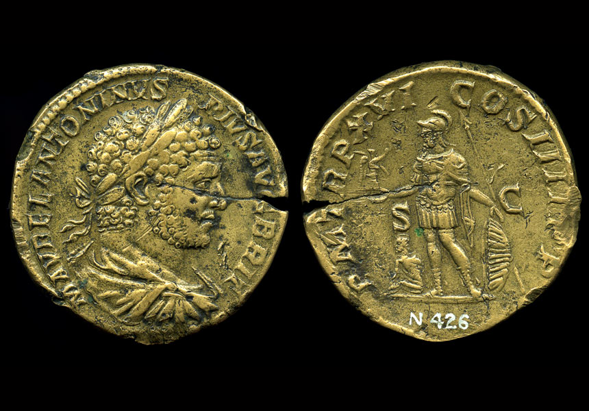 A depiction of Roman emperor Antoninus appears on one side of a worn, gold-coloured coin.
