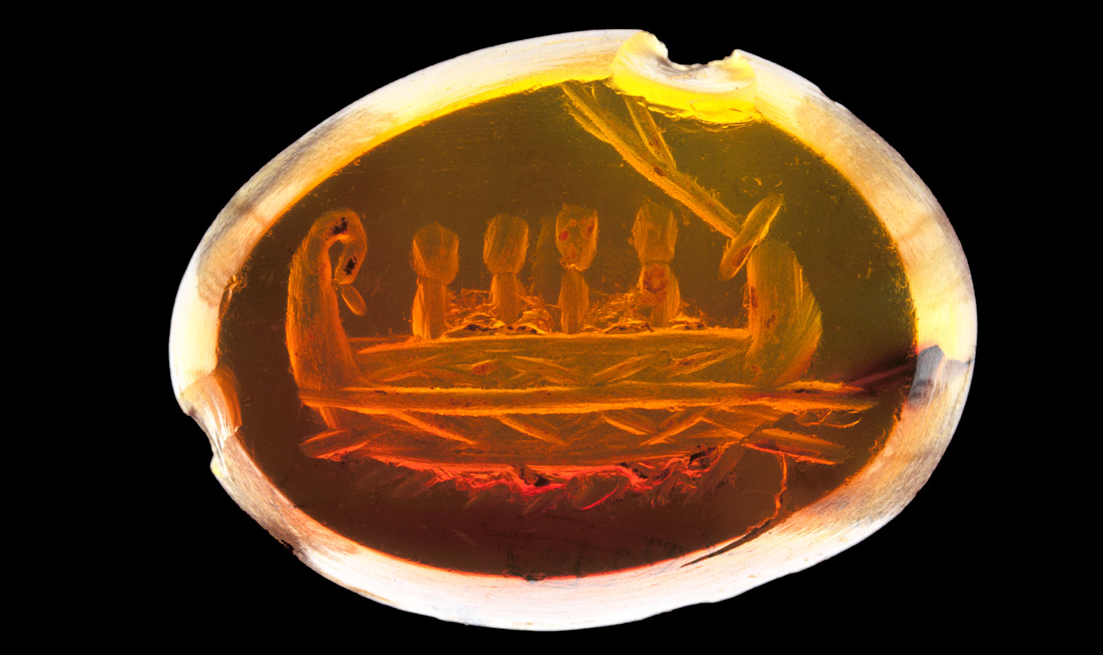 Carved orange gemstone showing a Roman warship, rowed by four marines.
