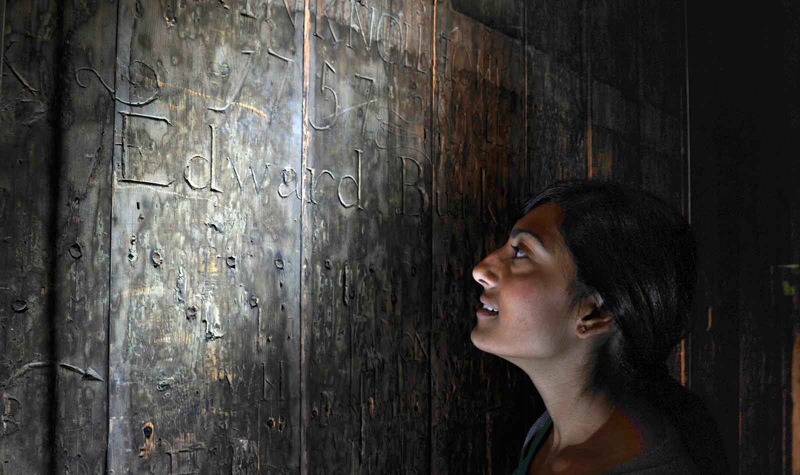 The remarkable wooden walls of the cell reveal the graffiti of the prisoners.