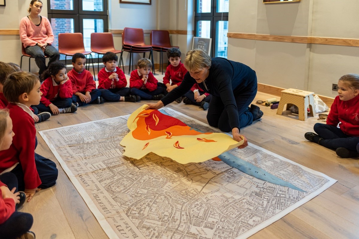 group of school children watching a facilitator place an image of fire over a map of London