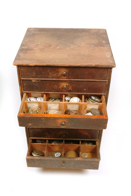 Watchcasemaker's chest of drawers. This set of drawers, containing watch movements and materials, was used at the Oliver family business of watchcase-makers. Richard J Oliver (1904-89) was the fourth generation of his family to become a watchcase-maker. Richard joined the firm at 31 Wynyatt Street, Clerkenwell in 1920. In 1941, the business moved to a larger workshop at 25 Spencer Street and, in 1949, Richard took over the business from his father. He remained at Spencer Street until 1971, when compulsory purchase by Islington council forced the sale of part of the workshop.