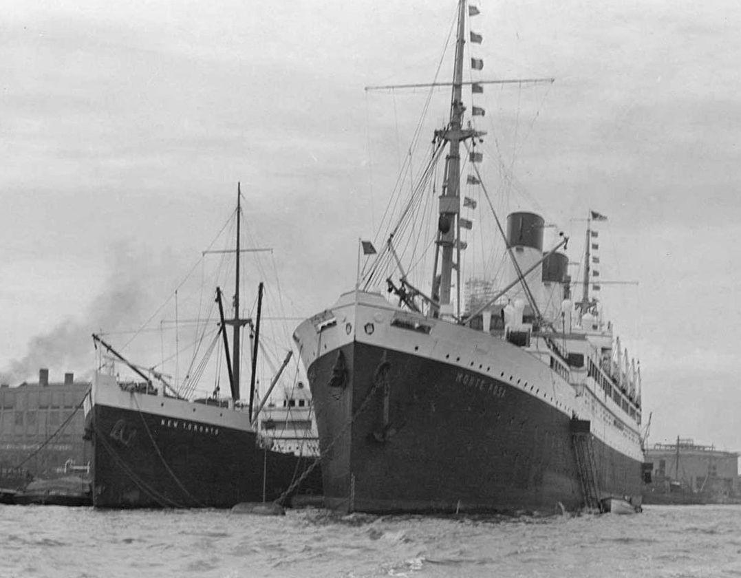 Black and white photo of the Empire Windrush ship docking into a port.