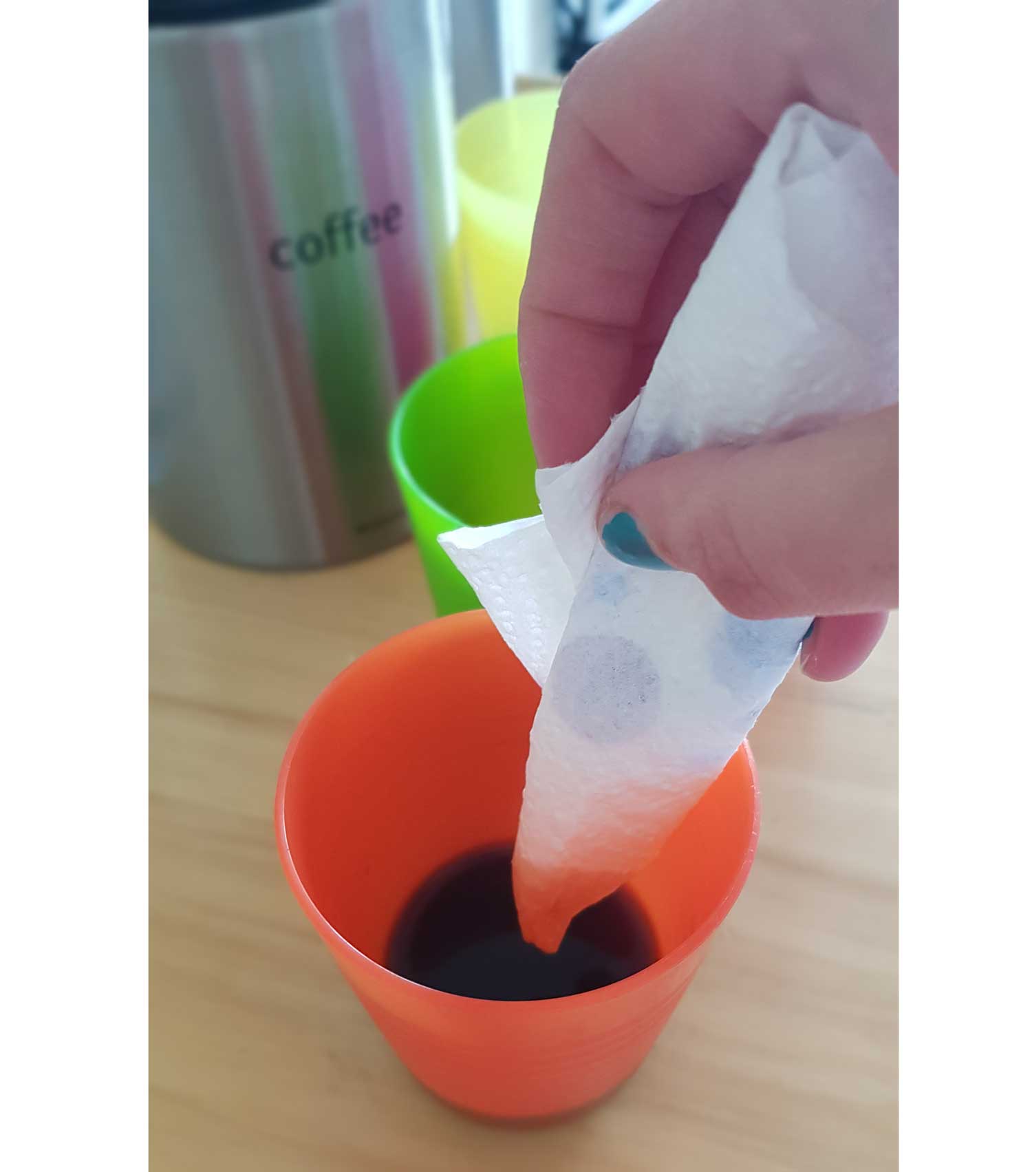 A roll of kitchen roll being dipped into a cup of tea.