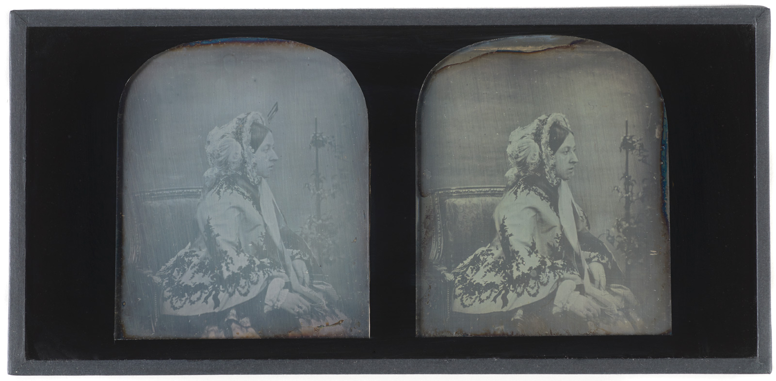 Hand-tinted stereoscopic daguerreotype of Queen Victoria, c. 1850, by Antoine Claudet.  Bookshaped, expanding case of dark blue leather. Decorated with gilt. Brass clasp. Opens to reveal two daguerreotypes and pair of binoculars. Case lined with purple velvet. Leather spine broken. One picture speckled with black.