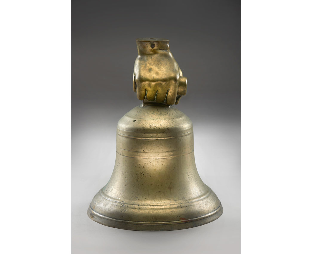 A bell surmounted by a mount in the shape of a human hand.