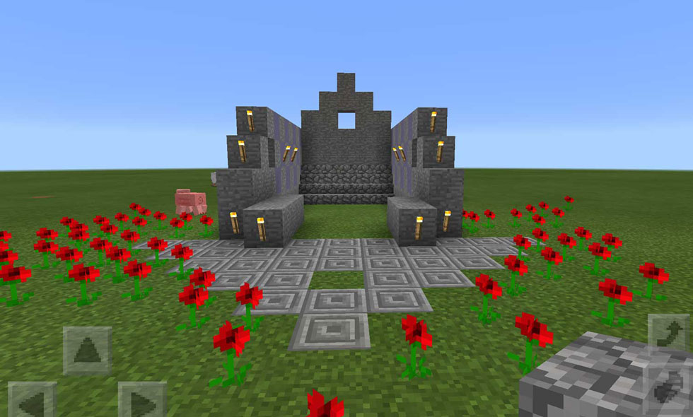 Screenshot of a Minecraft game in progress, where a stone arch has been built surrounded by red flowers.
