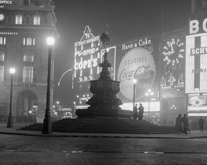 The statue of Eros in Piccadilly with the advertising lights in the background. The first illuminated advertising boards were built here in 1910 and Coca Cola, whose sign can be seen here, have the longest continuous presence at Piccadilly with an advert here continually since 1955. The Guinness Clock advert which can also be seen, was installed in 1955 and was the first of a number of legendary Guinness adverts to have moving parts. As well as a clock face it featured a zoo keeper with 2 juggling sea lions. The clock face was replaced in 1959.
