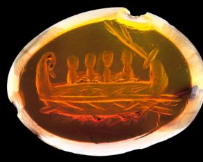 Carved orange gemstone showing a Roman warship, rowed by four marines.