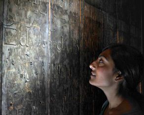 The remarkable wooden walls of the cell reveal the graffiti of the prisoners.